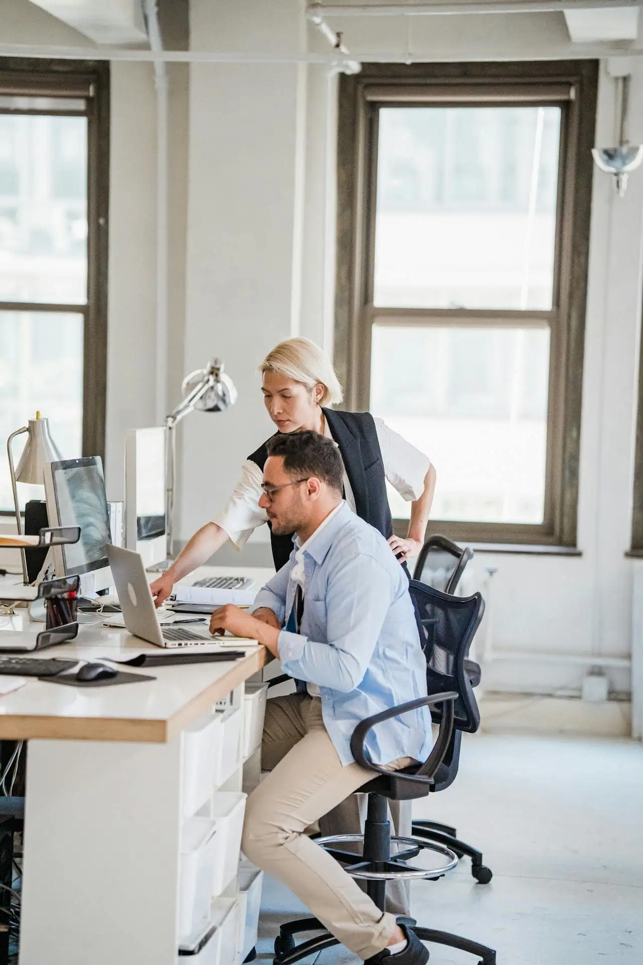 Colleague pointing at laptop screen during office discussion