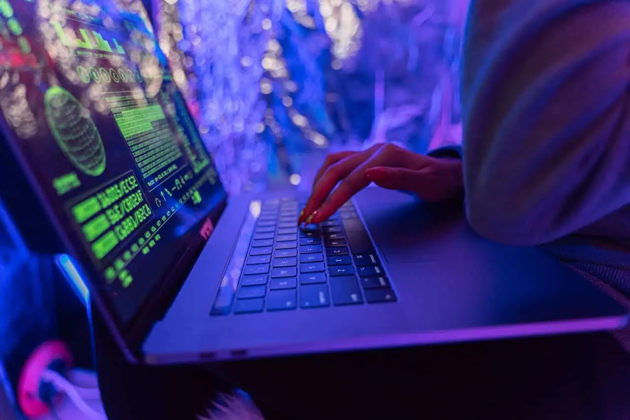 Close-up of hands typing on laptop with code displayed